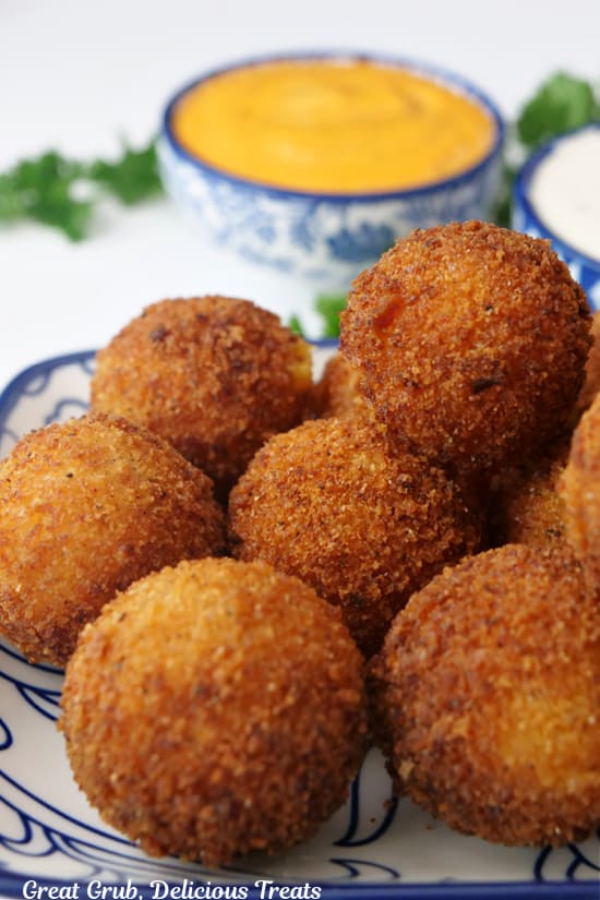 A close up of a stack of fried cheese bites on a white and blue plate.