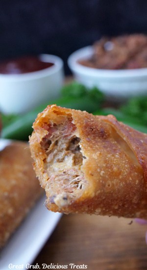 A fried brisket egg roll with a bite taken out of it.