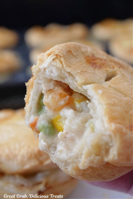 A close up of a mini pot pie with a bite taken out of it.
