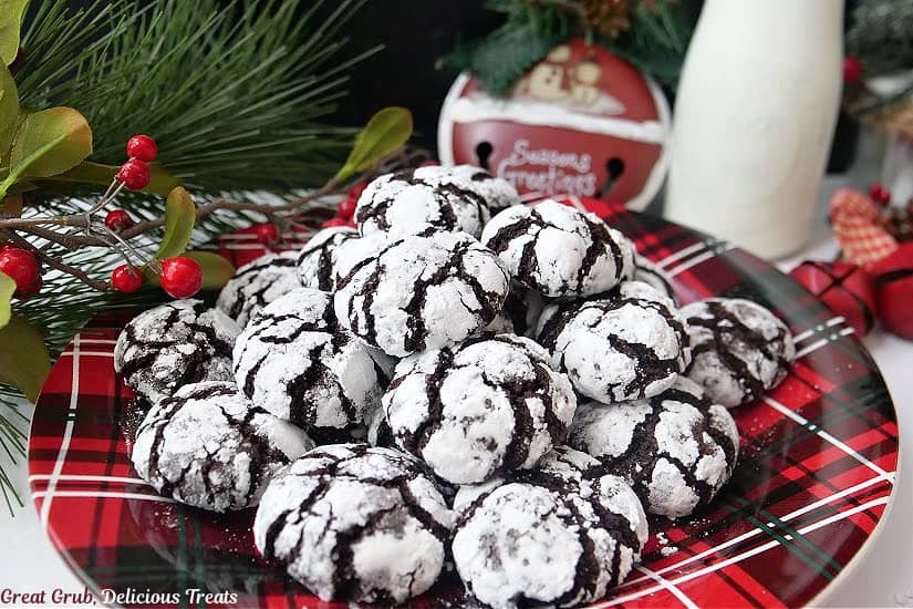 A horizontal photo of mini chocolate crinkle cookies on a red and black plaid plate.