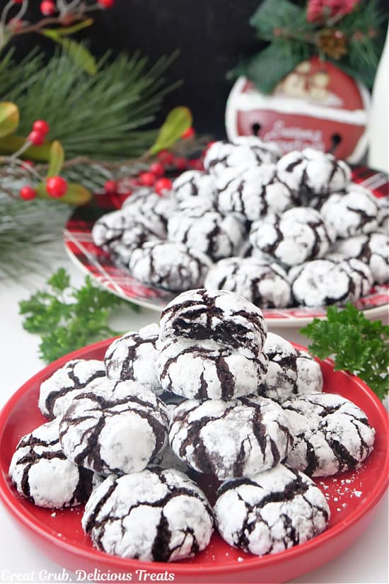 Two red round plates with a couple dozen mini chocolate crinkle cookies on them.
