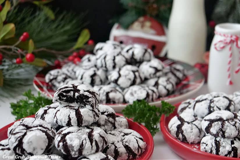 A horizontal photo of three red round plates with crinkle cookies on them.