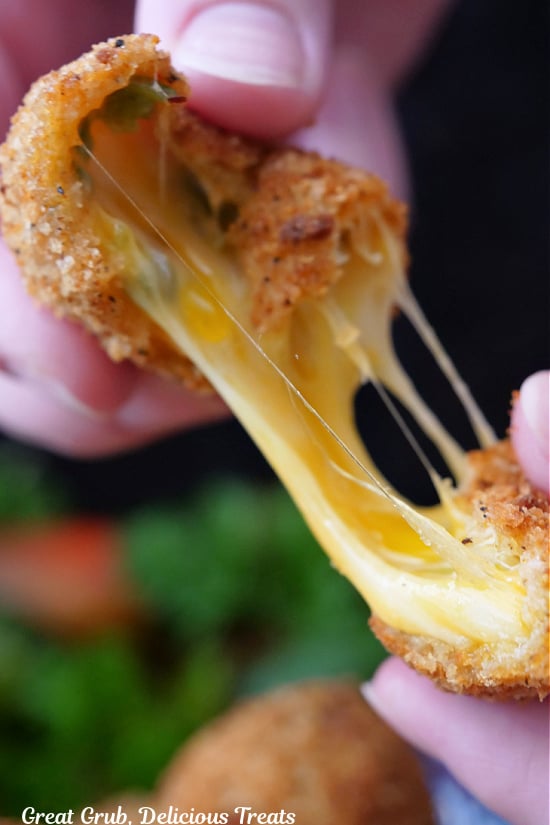 A crispy copycat rattlesnake bite being pulled apart showing the gooey cheese inside.