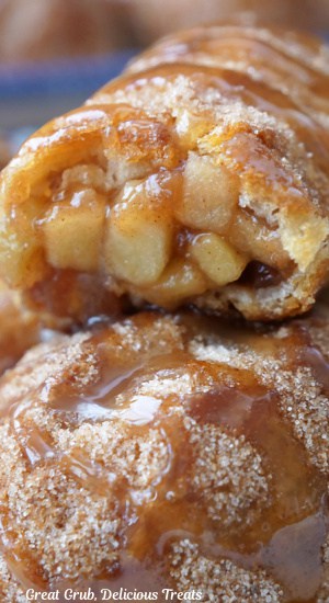 A close up of two crescents filled with apple pie filling with a bite taken out of the top one.