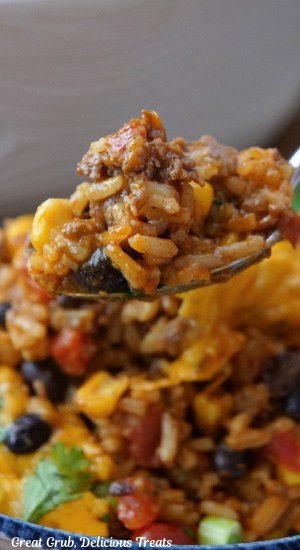 A close up of a spoonful of ground beef, rice, beans, corn.