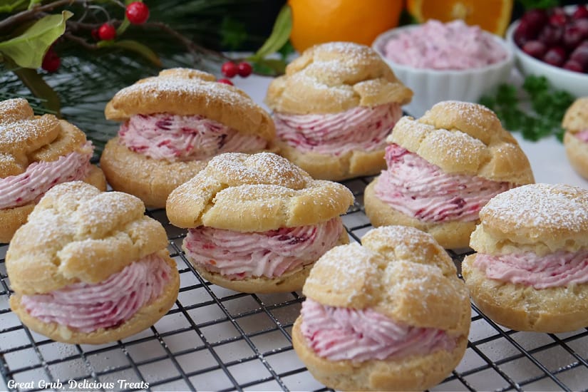 A wire rack with eight cranberry mousse filled cream puffs.