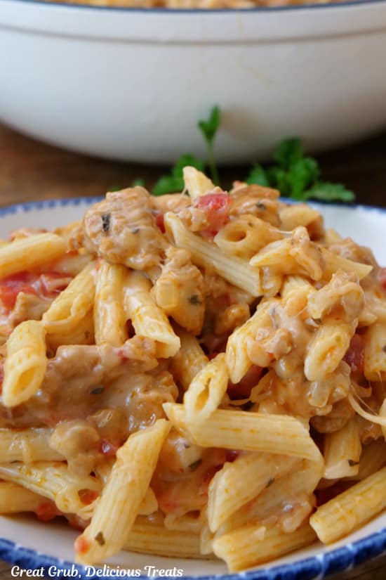 A close up of a serving bowl filled with Italian sausage pasta.