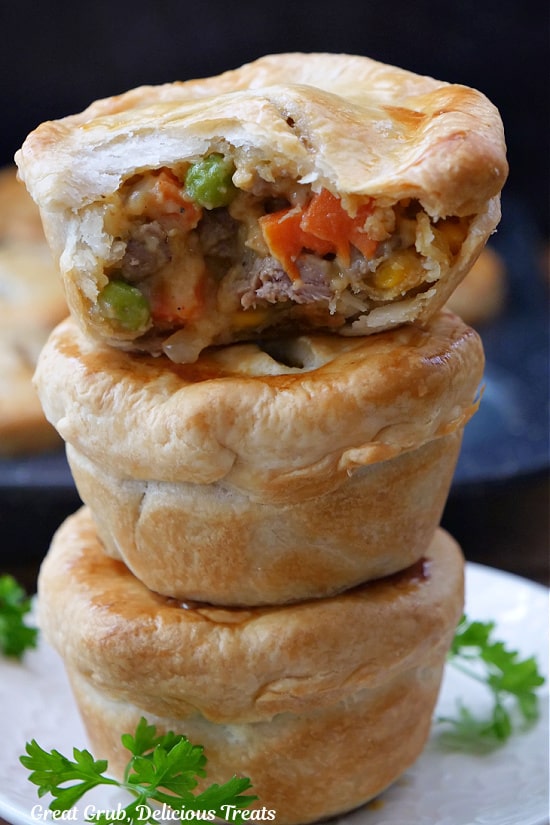 A stick of three mini beef pot pies with a bite taken out of the top one.