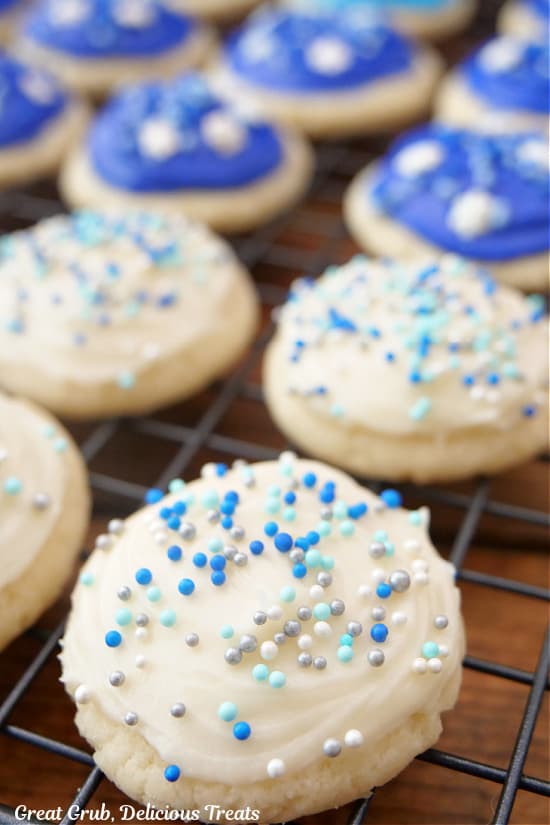 A wire rack with a half a dozen bite-size frosted sugar cookies on it.