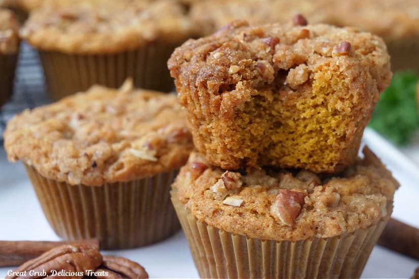 A horizontal photo of pumpkin muffins on a white plate with more muffins in the background.