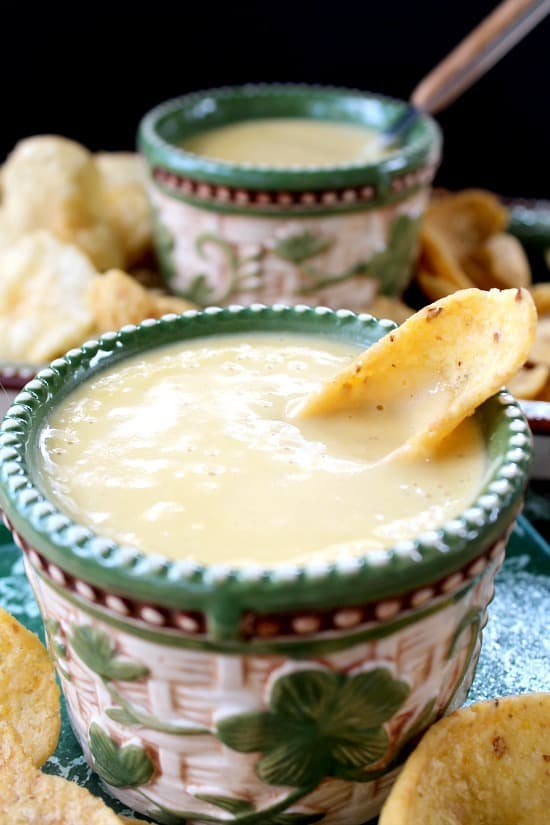 A close up of a small ramekin filled with healthy cheese sauce with a Frito in it.