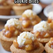 A white plate with blue trim with six bite-size cookie up filled with apple pie filling.