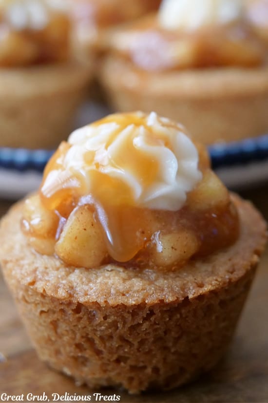 A close up of a apple pie cookie bite with apple filling, frosting, and caramel sauce.