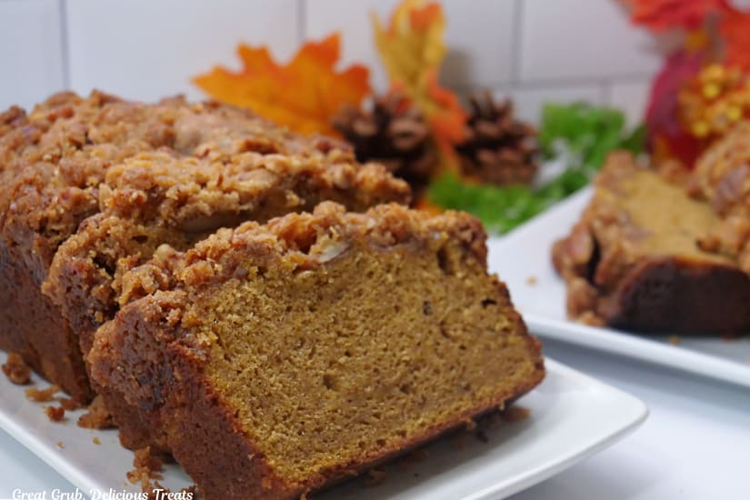 A horizontal photo of butternut squash bread on a white plate with fall decor in the background.