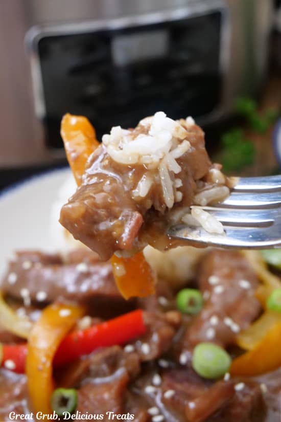 A close up of a bite of beef peppers and rice on a fork.