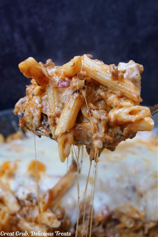 A heaping spoonful of cheesy pasta being scooped out of the