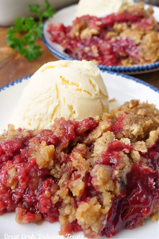 A close up of a bowl filled with raspberry crumble with vanilla ice cream.