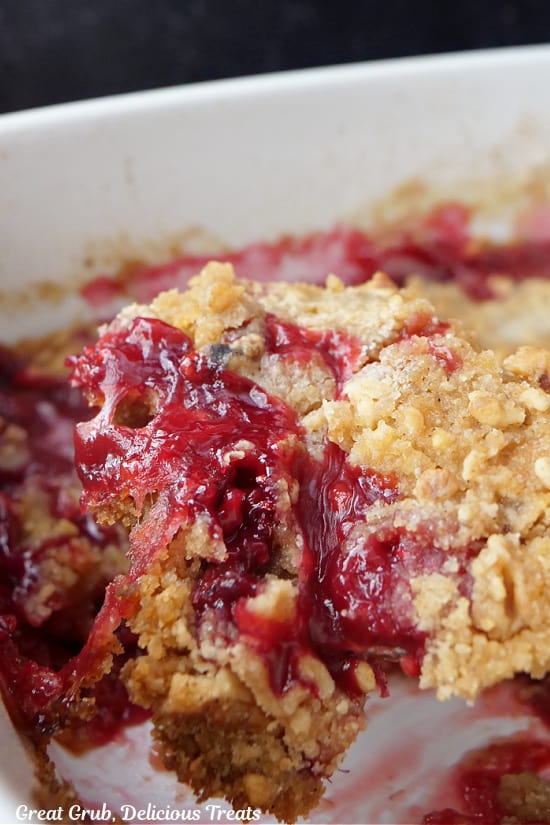 A serving spoon scooping out a helping of raspberry crumble.