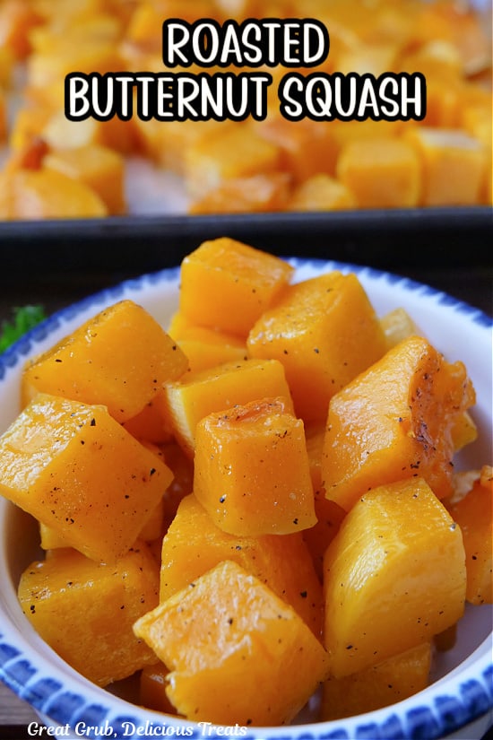 A white bowl with blue trim filled with a serving of roasted butternut squash cubes.