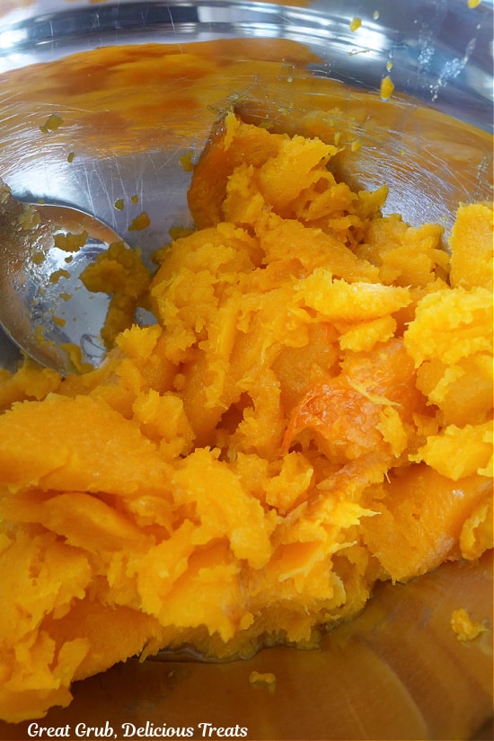 A silver mixing bowl filled with roasted butternut squash.