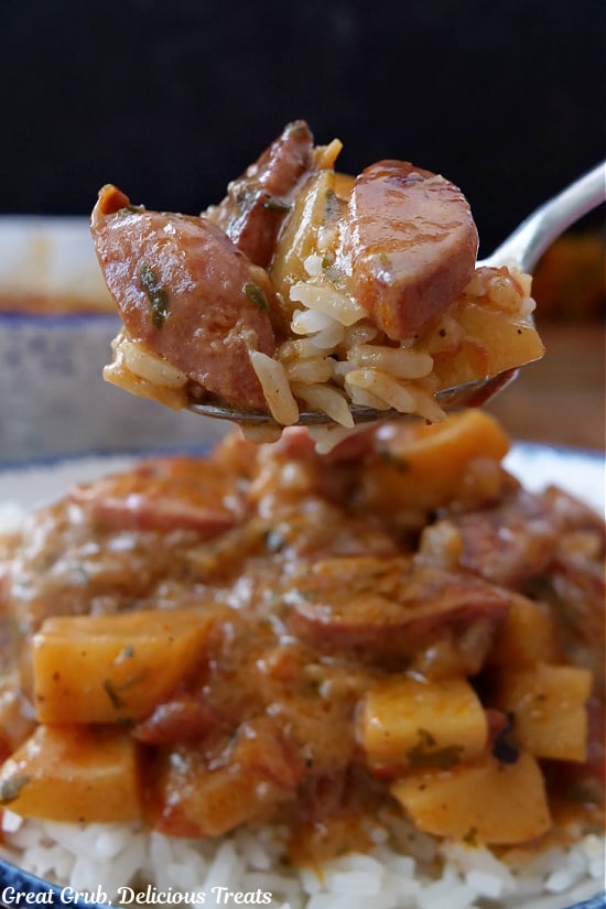 A close up of a spoonful of smoked sausage, potatoes, and rice.