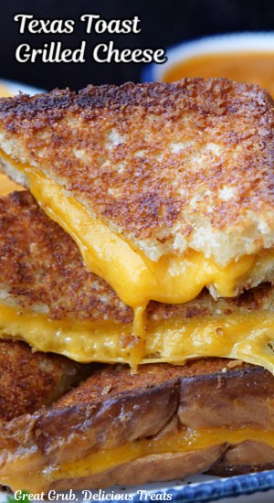 A stack of cheesy grilled cheese sandwiches piled on each other showing the gooey cheese.