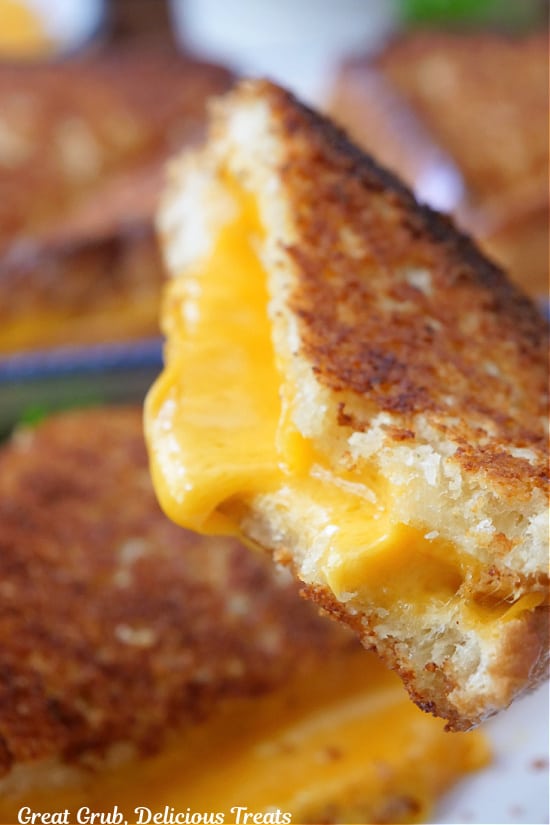 A close up of a half of grilled cheese with a bite taken out showing all the melted cheese.