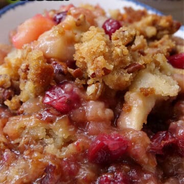 A white bowl with blue trim with a serving of apple cranberry cobbler in it.