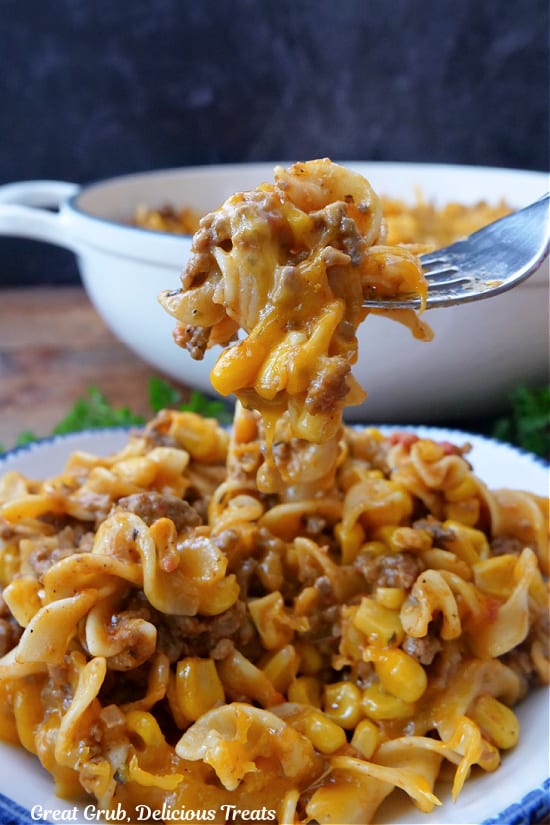 A fork with a bite of beef noodle casserole on it.