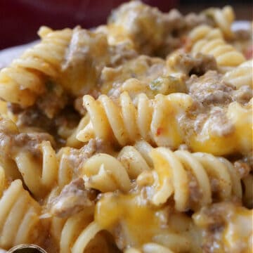 A close up of rotini pasta, ground beef, cheese and more, in a creamy sauce.