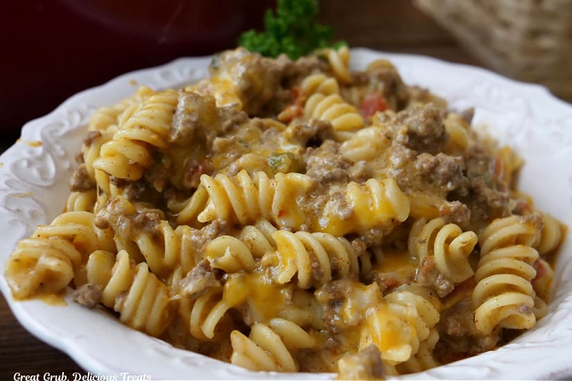 A horizontal photo of a white bowl with a serving of pasta, ground beef, and cheese.