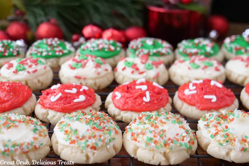 A horizontal photo of a wire rack with about a dozen bite-size cookies on it that have been frosted and sprinkled with festive sprinkles.