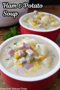Two red soup bowls filled with a serving of ham and potato soup.