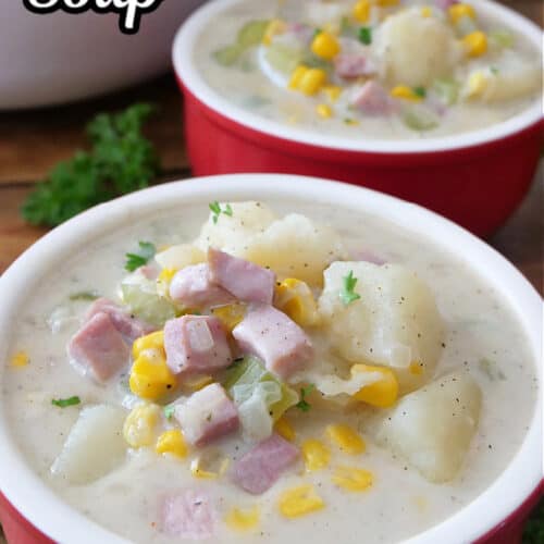 Two red soup bowls filled with a serving of ham and potato soup.