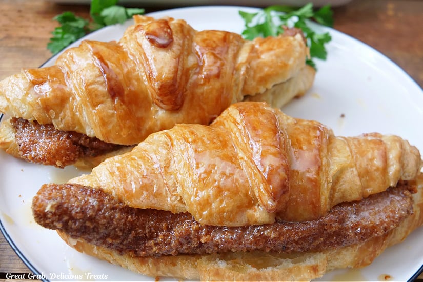 A horizontal photo of two croissants filled with fried chicken strips that are covered with honey butter.