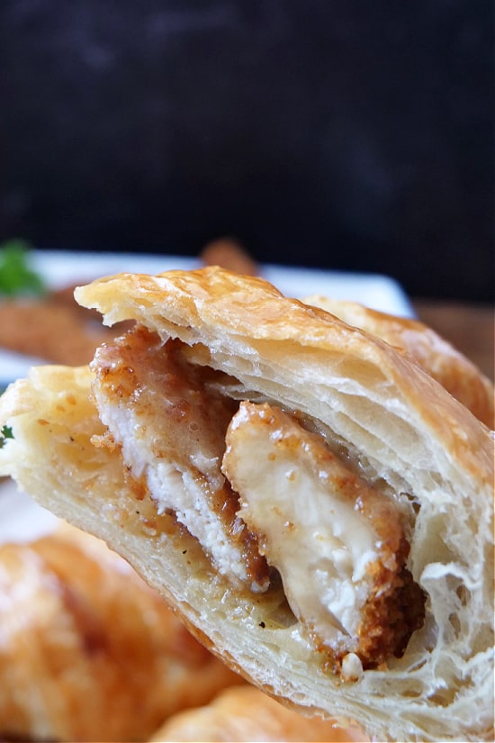 A close up a half croissant sandwich with fried chicken strips and honey butter.