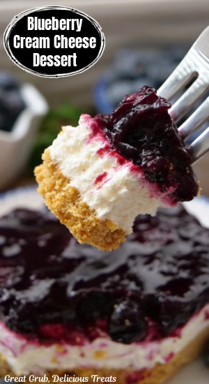 A fork with a bite of blueberry cream cheese dessert on it.