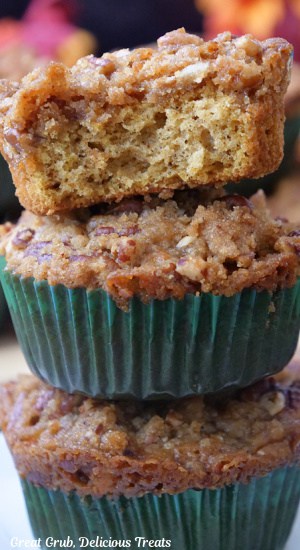 A close up of three muffins stacked on top of each other with a bite taken out of the one on top.