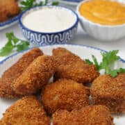 A white salad plate with blue trim with seven deep fried chicken nuggets on it.