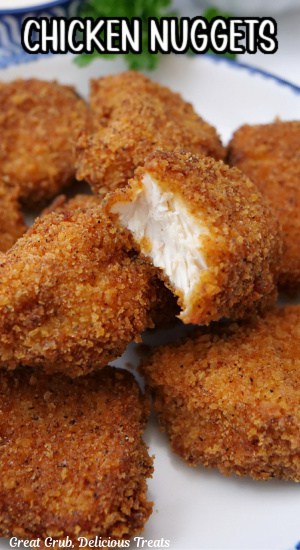 A close up of a plate with seven chicken nuggets on it with a bite taken out of one of the nuggets.