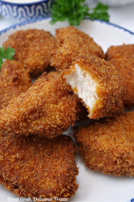 A close up of chicken nuggets with a bite taken out of one of them.