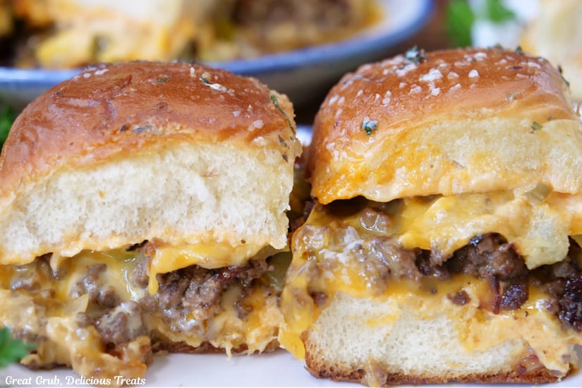 A close up of tow cheeseburger sliders on a white plate.