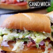 A close up of half a chopped Italian sandwich on a white plate with all the ingredients showing out of the sandwich.