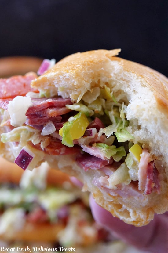 A close up of half a chopped Italian sandwich with a big bite taken out of it.