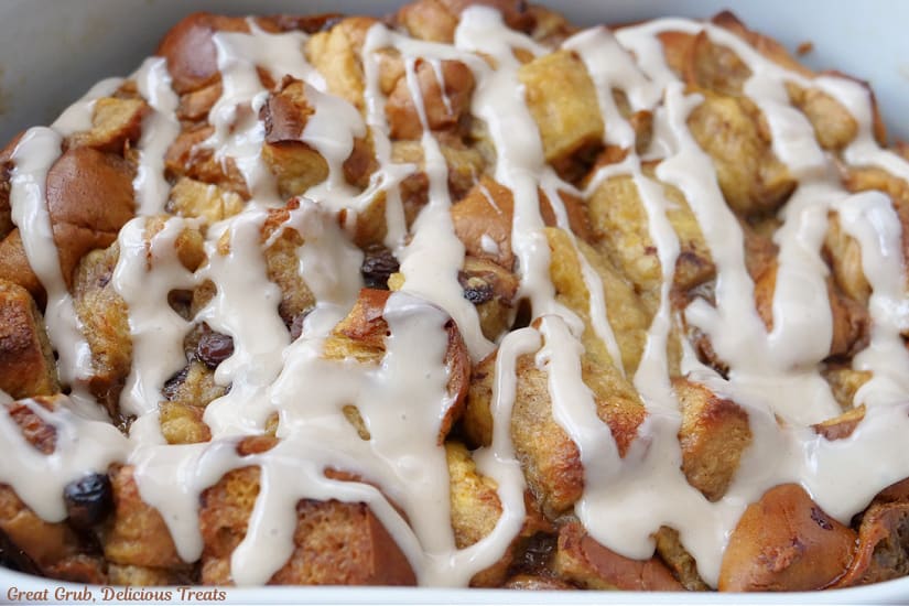 A horizontal photo of bread pudding in the baking dish with glaze drizzled over the top.