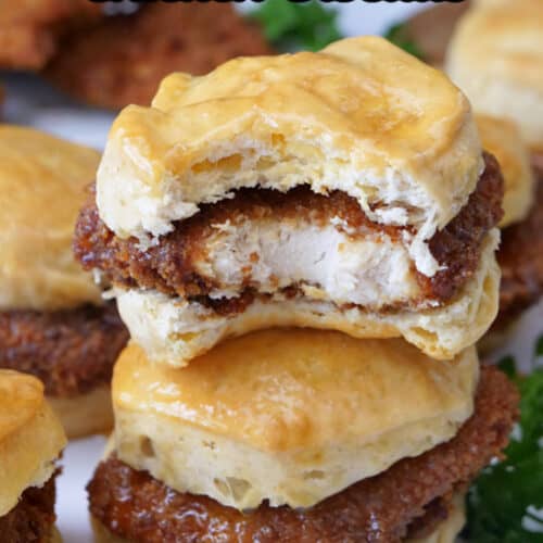 Two honey butter chicken biscuits stacked on top of each other with a bite taken out of the top one.