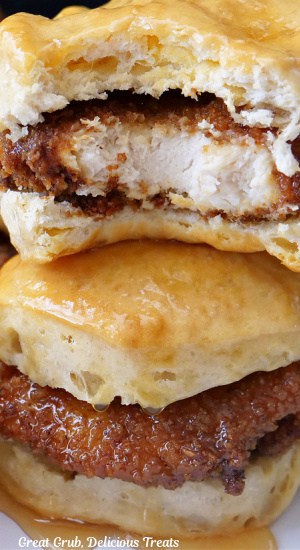 A super close up of two honey butter chicken biscuits with a bite taken out of the top one.
