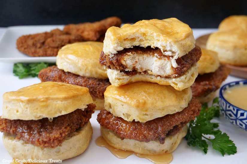 A horizontal photo of chicken biscuits on a white surface covered in honey butter.