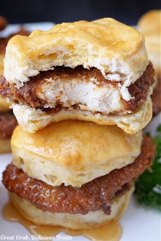 A close up of two honey butter chicken biscuits with a bite taken out of one of them.