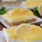 A close up of a few white plate with a slice of lemon cream cheese dessert on them.